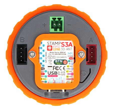 Chytrý ciferník M5Dial leží vzhůru nohama na bílém pozadí.